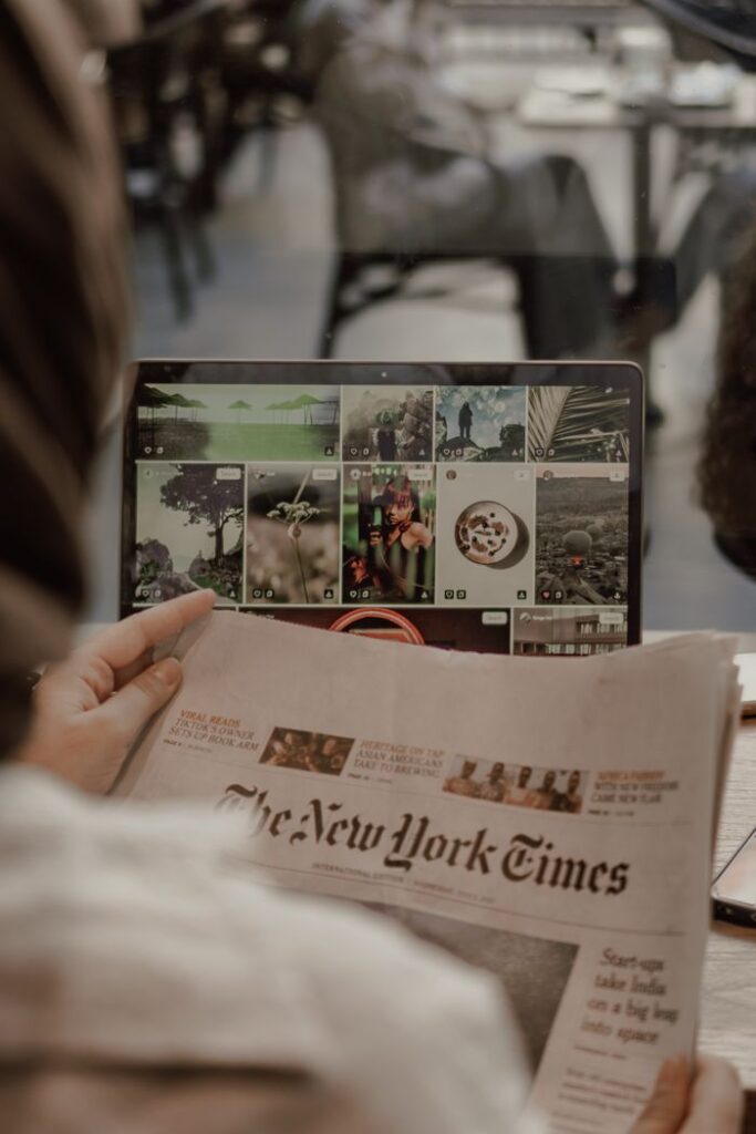Crafting Captivating Headlines: Your awesome post title goes here Woman reading The New York Times with a laptop displaying images in a café setting.